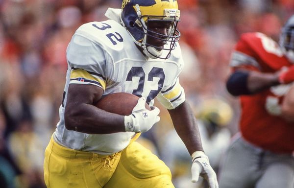 Football player in maize and blue uniform running with the ball.
