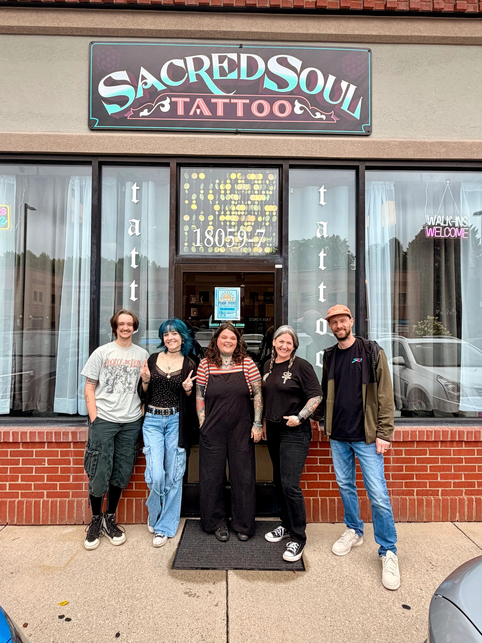 Group outside Sacred Soul Tattoo shop smiling.