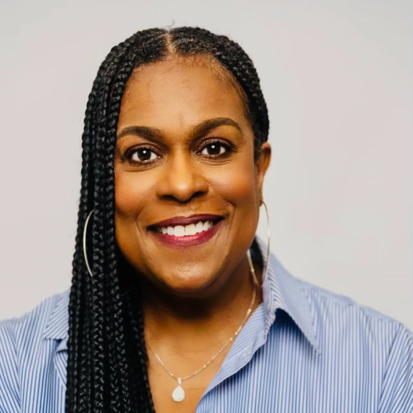 Smiling woman with braided hair wearing hoop earrings and a striped shirt.