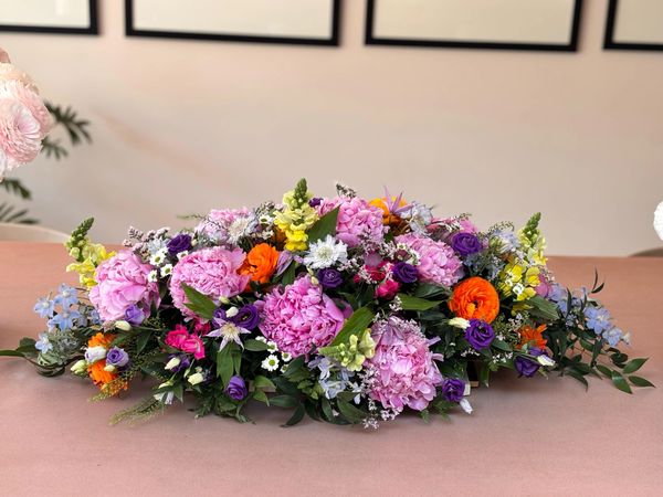 A vibrant floral arrangement with pink, orange, purple, and yellow flowers on a table.