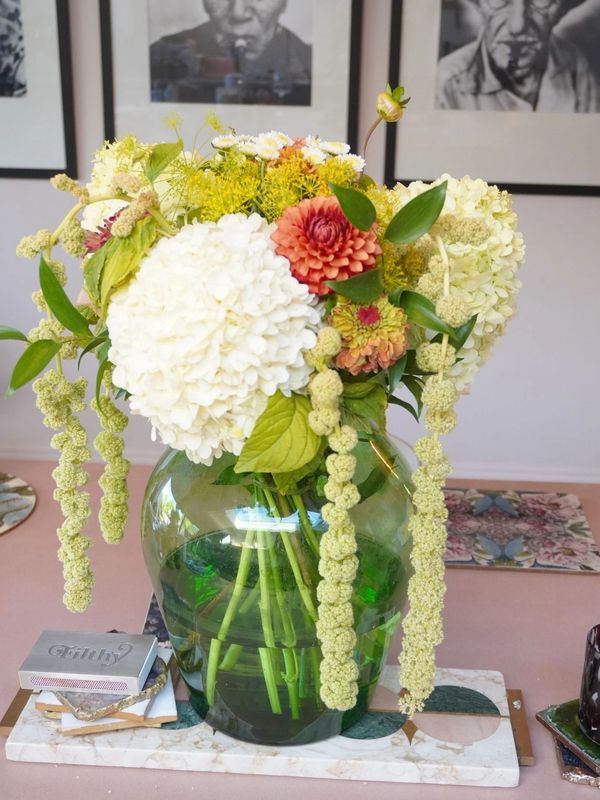 A vibrant floral arrangement in a green glass vase on a table.