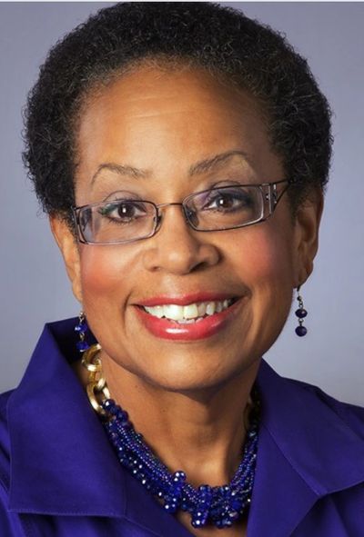 Smiling woman with glasses in purple attire.