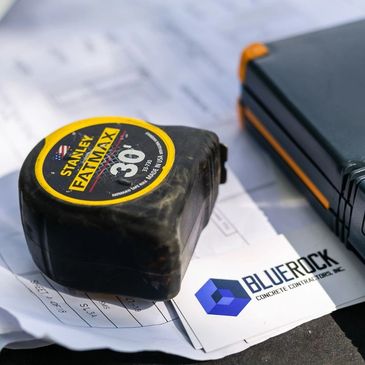 A Stanley FatMax tape measure on construction plans with a BlueRock business card.