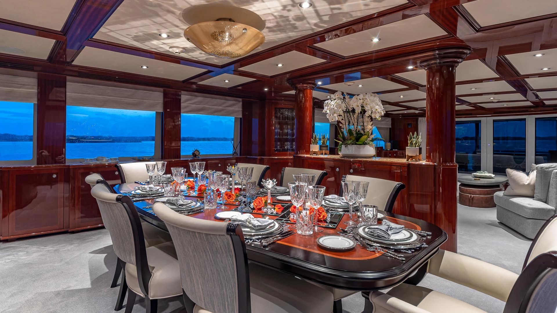 Elegant yacht dining room with polished wood and sunset views.
