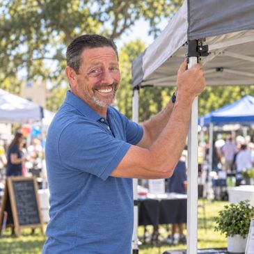 Man setting up a tent at an outdoor market.