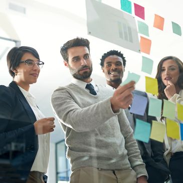 Team collaborating and brainstorming using sticky notes on a glass wall.