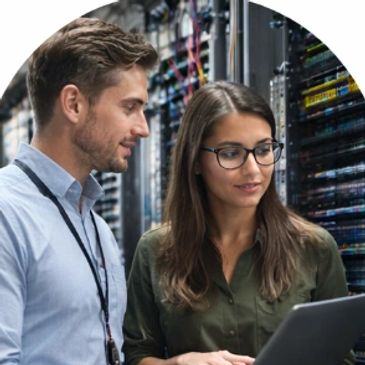 Two IT professionals collaborating in a server room, reviewing data on a tablet.