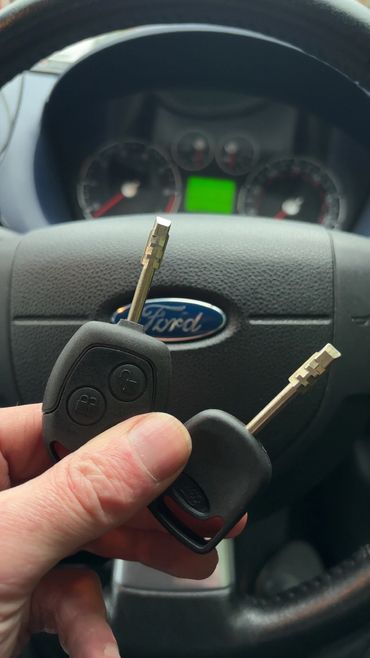 Hand holding two Ford car keys inside a Ford vehicle.