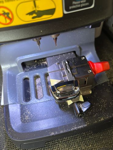 Close-up of a key-cutting machine with drill bits and key holder.