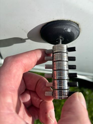 Person using a tool to measure or adjust a black circular object.