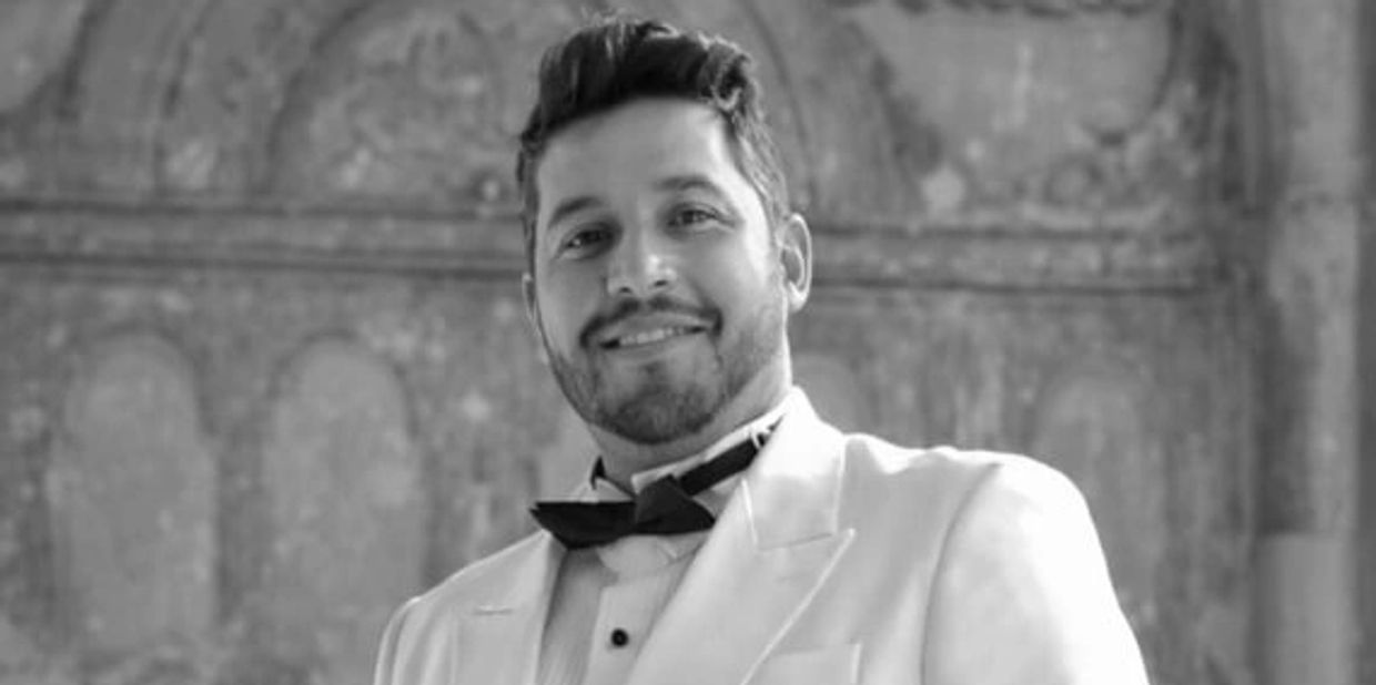 Hombre sonriente con esmoquin blanco.