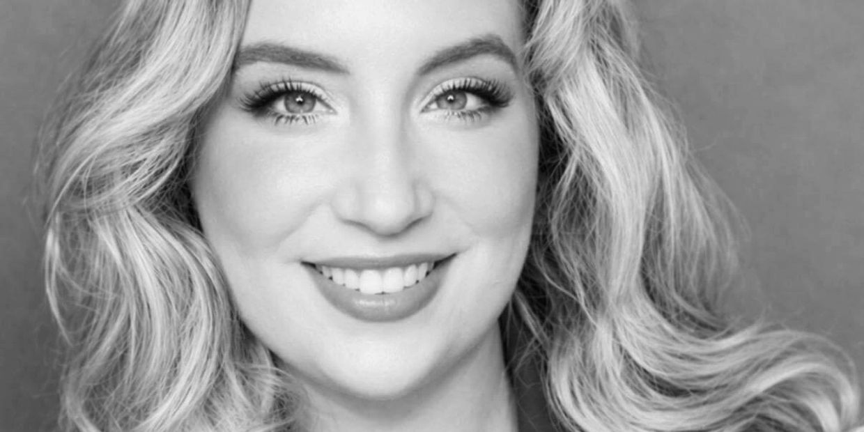 Black and white close-up portrait of a smiling woman with wavy hair.