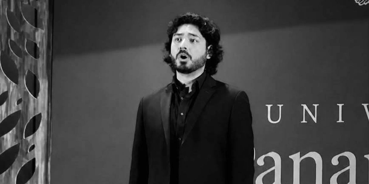 Hombre cantando con expresión emocional en evento formal.