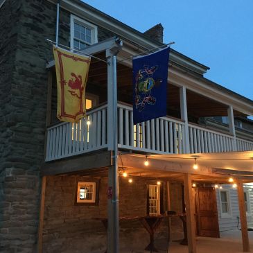 Flags hanging outside a stone building at dusk.