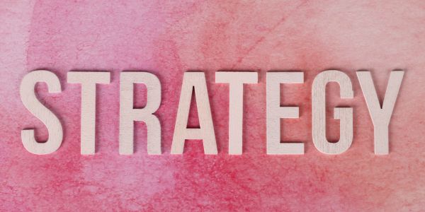 The word STRATEGY on a pink textured background.