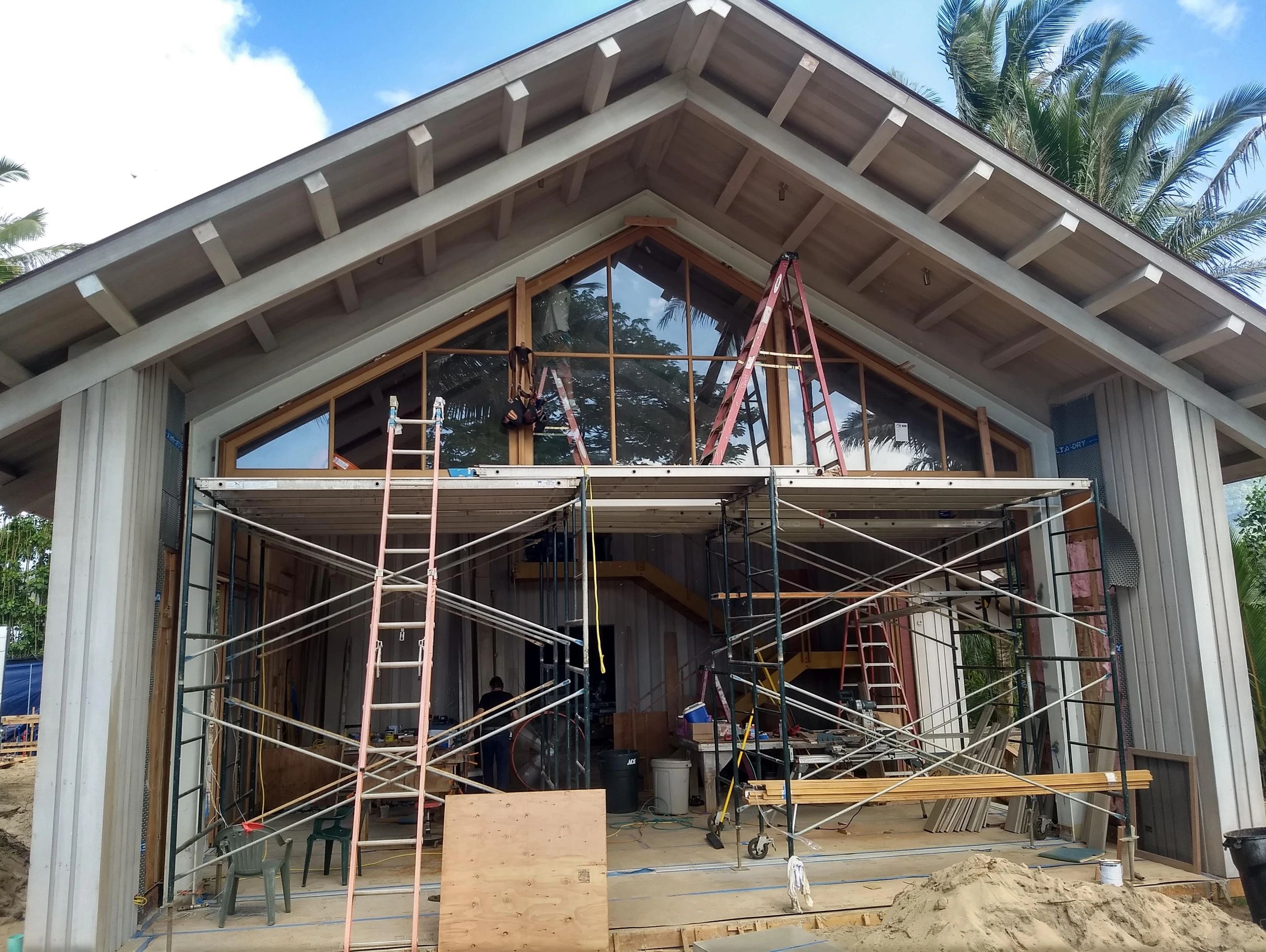 House under construction with scaffolding and ladders.