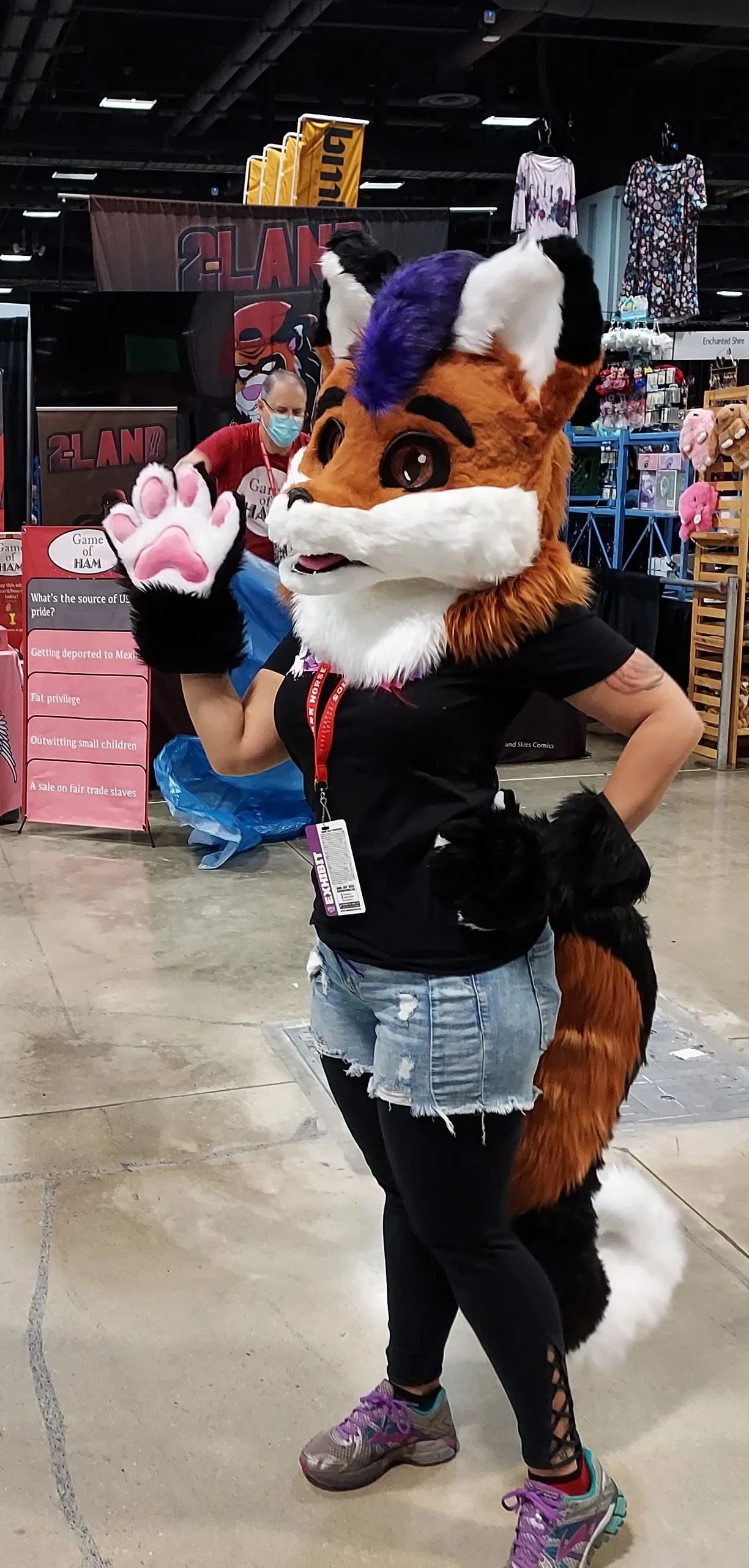 Person in a colorful fox costume waving at a convention.