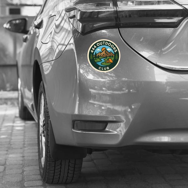 Car with a colorful 444 Outdoors Club sticker on the rear side in a black and white setting.