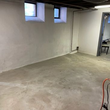 Empty basement room with concrete floor and small windows.