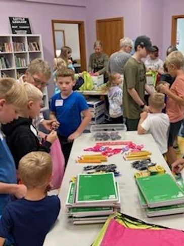 Group of children and adults at a school supply distribution event.