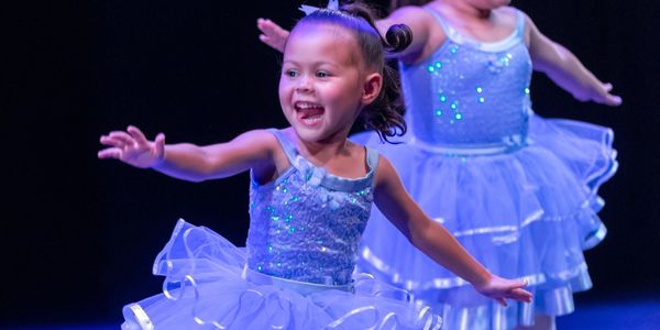 Young ballerinas performing on stage in sparkling blue tutus.