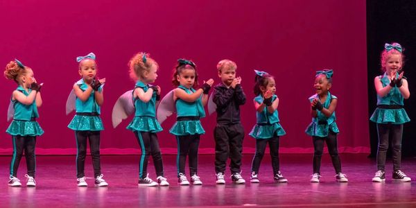 Young children performing a dance recital in blue costumes.