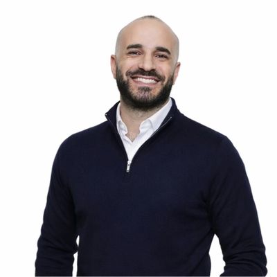 Smiling man in a dark sweater against a white background.