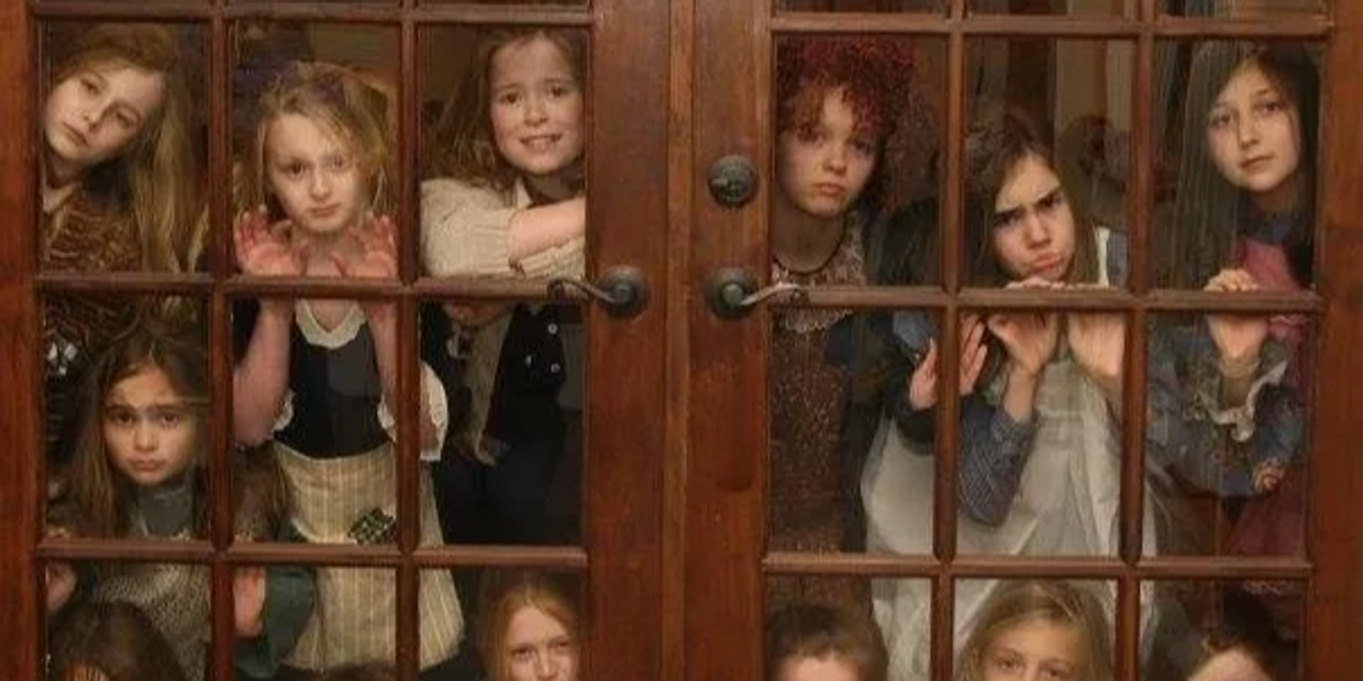 Group of young girls looking through glass doors with various expressions.