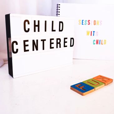 Lightbox with "Child Centered" text and colorful letters spelling "FUN" on table.