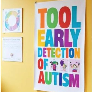 Colorful poster promoting early autism detection on a yellow wall.
