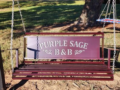 A purple swing bench with 'PURPLE SAGE B&amp;B' written on it.