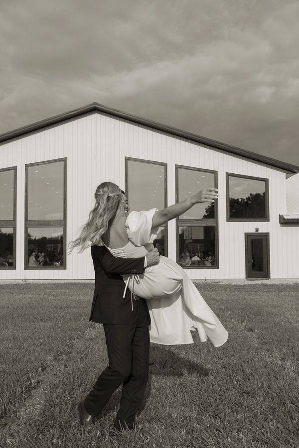Man lifting woman in front of a building.