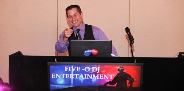DJ smiling and pointing while performing at a Five-O DJ Entertainment event.