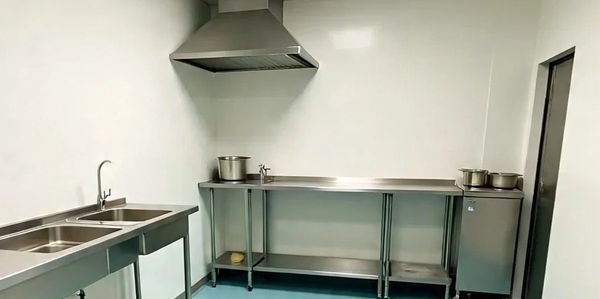 Clean and minimal industrial kitchen with stainless steel countertops and blue flooring.