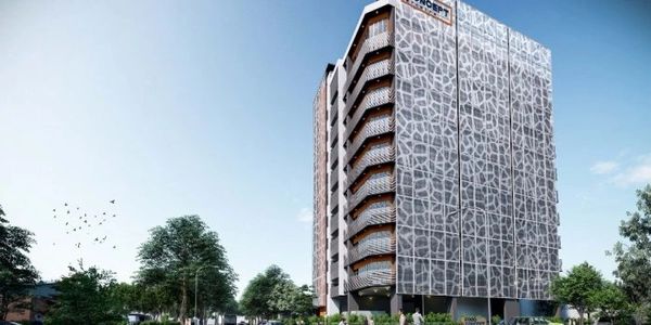 Modern multi-story building with unique geometric facade under a clear blue sky.