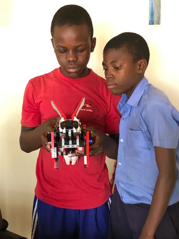 Two boys looking at a small brick model.