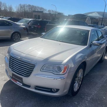 Silver Chrysler sedan parked in a sunny parking lot near a community complex.