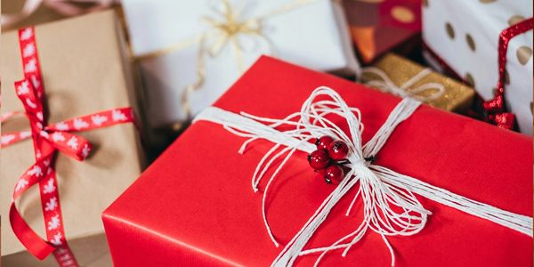 A close-up of various wrapped holiday gifts with decorative ribbons and bows.