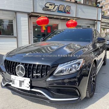 A sleek black Mercedes-Benz parked outside a shop with red lanterns.