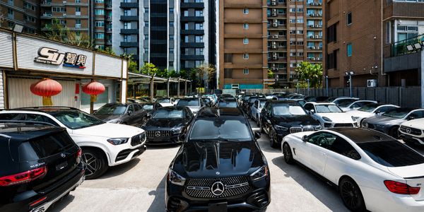 Luxury Mercedes-Benz cars parked in an urban lot surrounded by tall buildings.