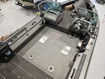 Interior of a fishing boat with steering console and seating area.