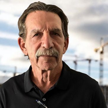 Older man with mustache and gray hair in black shirt.