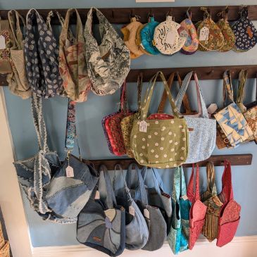 Colorful cloth bags hanging on wooden racks.