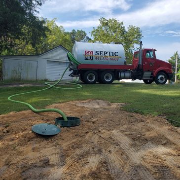 Septic truck servicing a residential septic system outdoors.