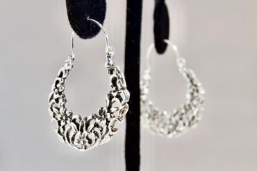 Close-up of silver floral hoop earrings.