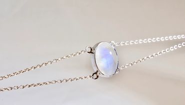 Close-up of a silver necklace with a moonstone pendant.