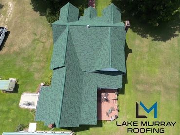 Aerial view of a house with green roofing and a patio.