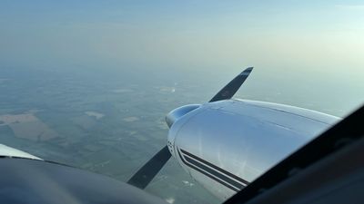 View from small plane window showing propeller and landscape.