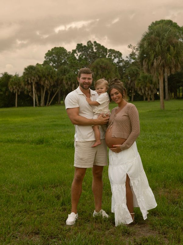 Happy family outdoors with pregnant mom and toddler.