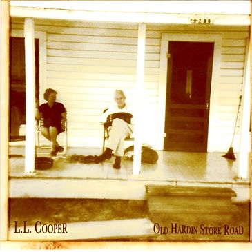 A sepia-toned photo of two people sitting on the porch of a white clapboard building.
